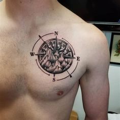 a man's chest with a compass tattoo on his left side and an image of mountains in the middle