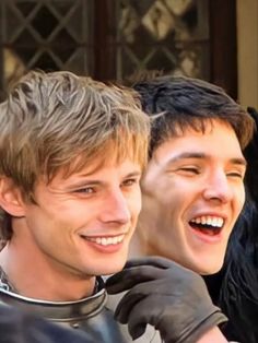 two young men are smiling and wearing black gloves