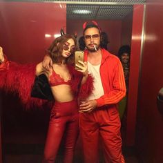 a man and woman dressed up in devil costumes taking a selfie with a cell phone