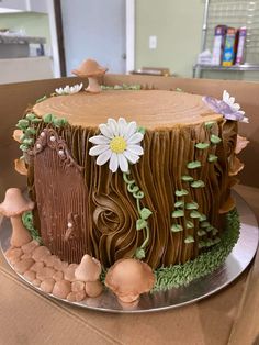 a cake decorated with icing and flowers on top of a cardboard box in the shape of a tree stump