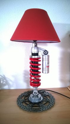 a red lamp sitting on top of a wooden table next to a bike chain and sprock