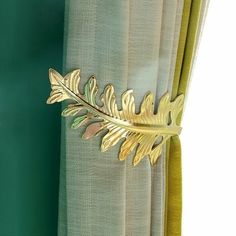 a curtain with a gold leaf decoration on the top and bottom of it, next to a green wall