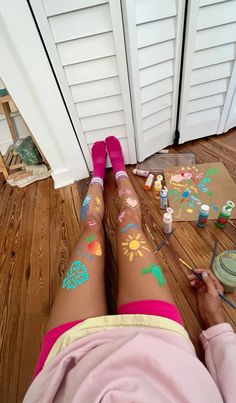 a woman with her legs covered in flowers and paint sitting on the floor next to a door