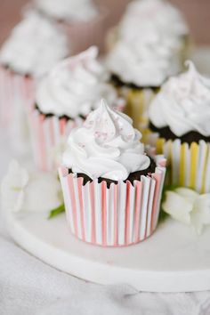 several cupcakes with white frosting on a plate