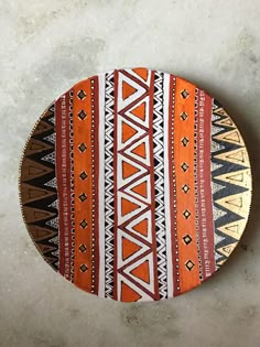 an orange and white plate with designs on the top is sitting on a concrete surface