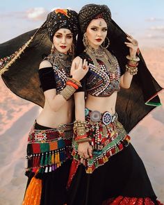 two women dressed in belly dance clothing posing for the camera with their arms around each other