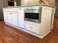 a kitchen with white cabinets and stainless steel stove top oven in the center of the room