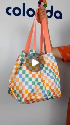 a woman is holding up a colorful bag