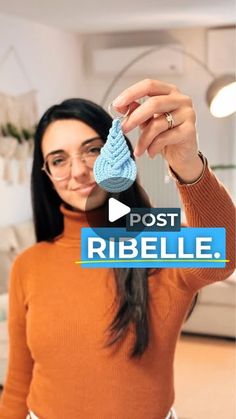 a woman holding up a blue crocheted object in her hand with the words post ribelle on it