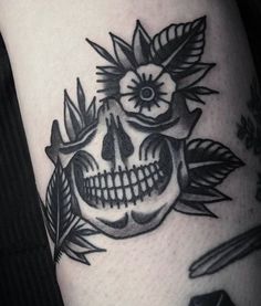 a black and white skull with flowers on it's head, surrounded by leaves