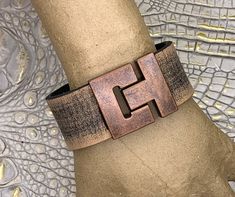 I spend a great deal of time searching for unique jewelry and bag components. Combining vintage finds with new results in many one-of-a-kind pieces. Striking 1-1/8" wide heavy leather cuff bracelet features distressed taupe brown buffalo leather strap. Heavy leather strap is 3mm (about 1/8") thick. It keeps its shape. 33mm tall matte antique copper plated zinc toggle clasp has magnetic for extra security. Size 7-1/2". Hand crafted! Thank you for visiting - message me if you have a question. Buff Adjustable Bracelet With Antique Finish, Unique Adjustable Bracelets With Antique Finish, Unique Adjustable Bracelet With Antique Finish, Adjustable Brown Metal Cuff Bracelet, Vintage Nickel Free Cuff Jewelry, Vintage Nickel-free Cuff Jewelry, Nickel-free Vintage Cuff Jewelry, Elegant Adjustable Patina Cuff Bracelet, Elegant Adjustable Cuff Bracelet With Patina