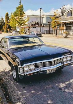 an old black car is parked on the side of the road