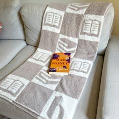 a book sitting on top of a couch next to a white and gray blanket covered in squares