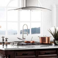 a kitchen island with pots and pans on it in front of a large window