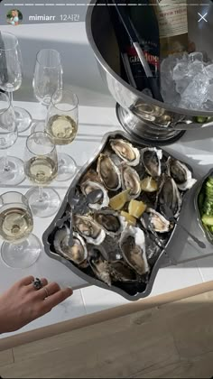 there is a platter of oysters on the table next to some wine glasses