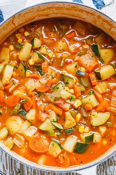 a pot filled with vegetable soup on top of a wooden table