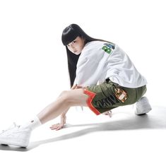 a woman in white shirt and green shorts sitting on the ground