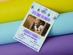 a birthday party ticket sitting on top of blue and yellow fabric, with an image of a child's face in the center