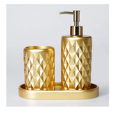 a gold bathroom set with two cups and a soap dispenser on a tray