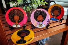 three plates with black women painted on them sitting on a table next to a potted plant