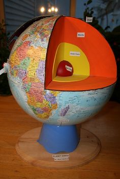 a model of the earth with an apple in it's center on a wooden table