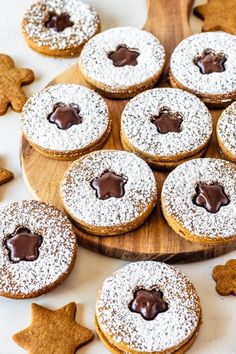 some cookies are on a wooden plate with chocolate icing and star shaped cookies in the background