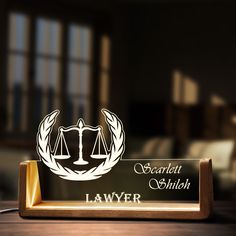 a wooden plaque with the name and symbol of a law firm on it in front of a window