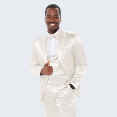 a man in a white tuxedo smiles at the camera while standing with his hands in his pockets