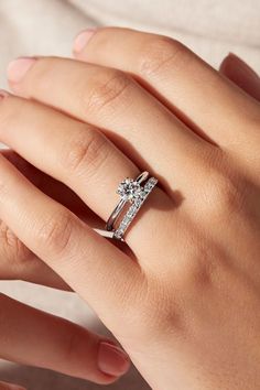 a woman's hand with a diamond ring on top of her finger and an engagement band