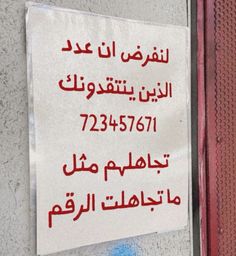 a sign posted on the side of a building in arabic writing and english characters below it