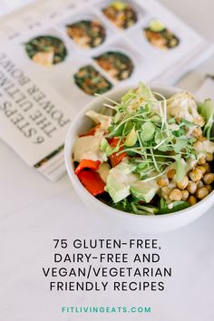 a white bowl filled with salad next to an open cookbook on top of a table