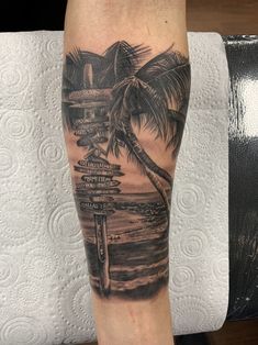 a man with a tattoo on his arm has a palm tree and street signs in front of him