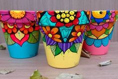 three colorful flower pots sitting on top of a table