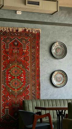 two plates are hanging on the wall next to a table with chairs and a rug