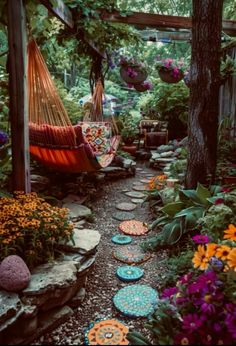 a hammock hanging in the middle of a garden filled with flowers and plants