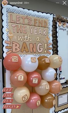 some balloons are hanging on the wall in front of a sign that says let's end the year with a bang