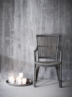 a chair sitting next to a tray with candles on it in front of a concrete wall