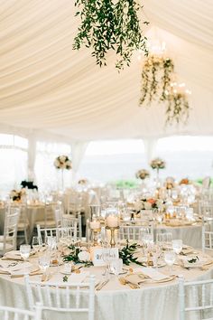 the tables are set with white linens and greenery for an elegant wedding reception