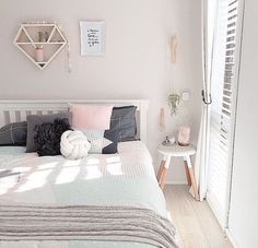 a bed room with a neatly made bed next to a white door and window sill