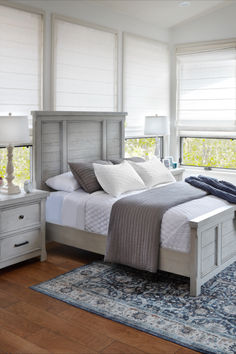 a bedroom with a bed, nightstands and two windows