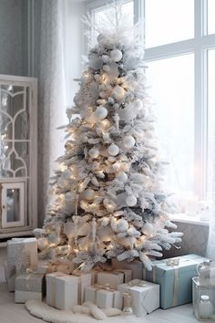 a white christmas tree with presents under it