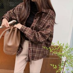 a woman carrying a brown bag while standing next to a building