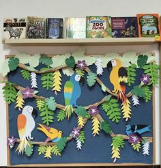 a book shelf filled with books and paper cut out parrots on the tree branch