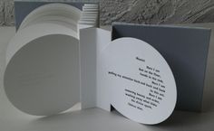 an open book with a poem on the front and back cover, sitting next to a stack of white plates