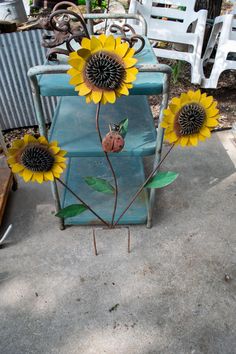 three sunflowers are placed on top of an old blue table and chair in the back yard