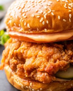 a chicken sandwich is stacked on top of each other with sesame seeds and cucumbers