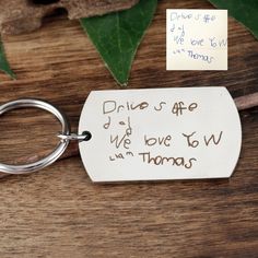 a keychain with a note attached to it sitting on a table next to leaves