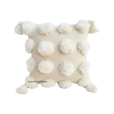 a white pillow with pom - poms on it