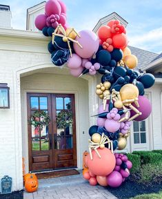 a large balloon arch in front of a house with pumpkins and balloons on it