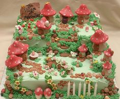 a birthday cake with green frosting and red mushrooms on the top, sitting on a table